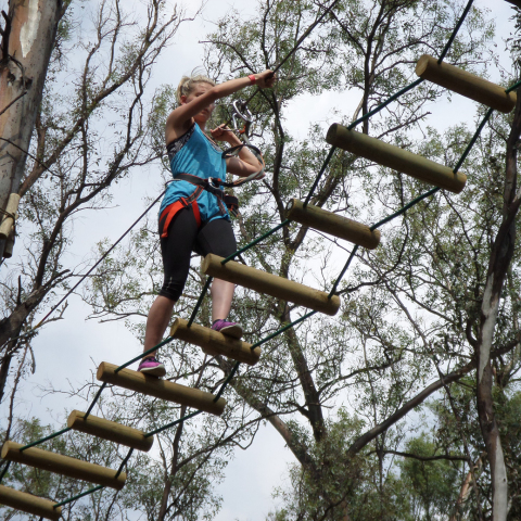 Client reaching new heights on the Blue Combo course at Acrobranch Casalinga, featuring treetop challenges and a ride on the Big Zip
